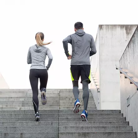 Bilden visar två personer som joggar uppför en trappa