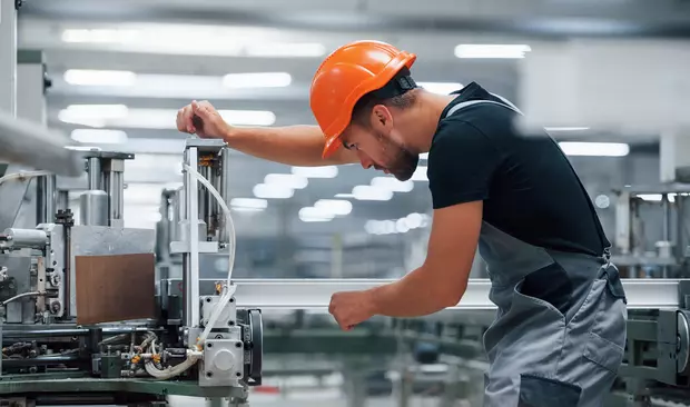 Operator of machine / industrial worker in an orange hard hat.