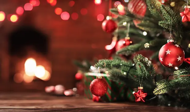 Bilden visar en julgran med en brasa i bakgrunden