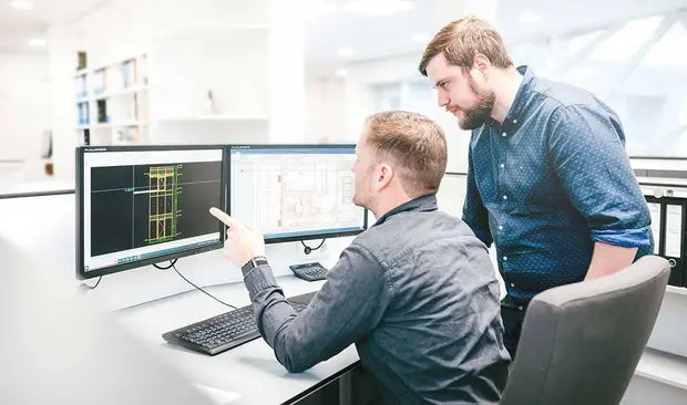 Zwei MZwei Männer stehen im Büro und schauen auf einen Bildschirm, auf dem das Zeichenprogramm CAD-Suite 2D geöffnet ist.