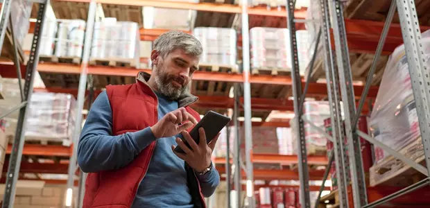 Man using tablet PC in store room to check stock